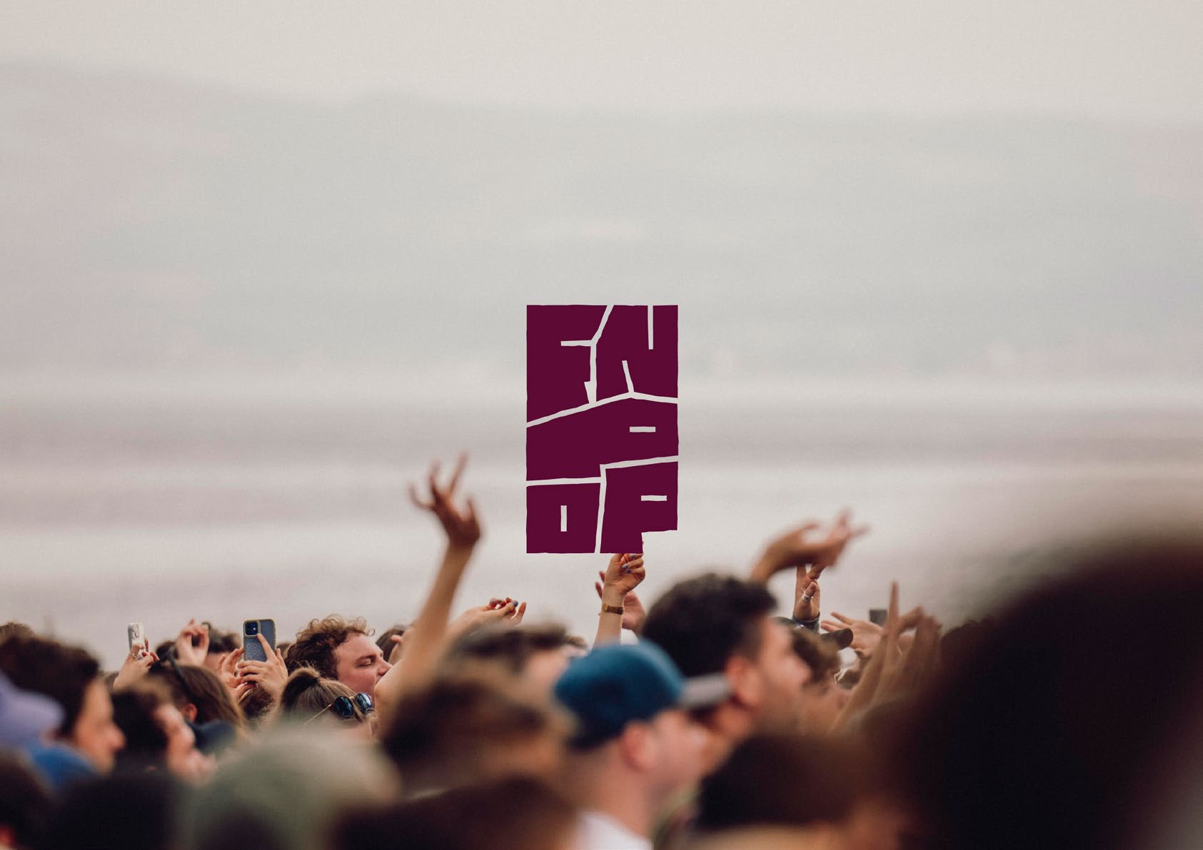 Feiernde Menge vor dem Bodensee, darüber ein hochgehaltenes FN:POP-Schild in Aubergine
